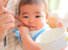 写真:離乳食を食べさせてもらう赤ちゃん