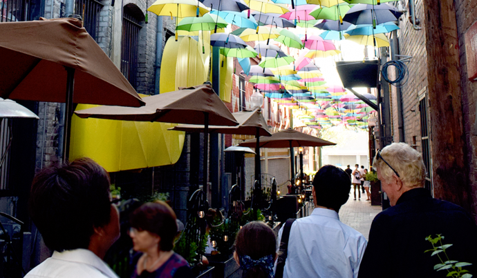 写真:色とりどりの傘でできた屋根の脇道