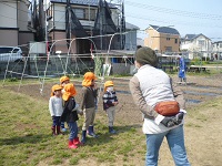 4歳児ぞう組がせせらぎ農園の方の話を聞いている写真