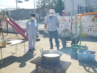 児童館の職員がかまどの火加減を見ている写真