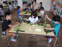 5歳児らいおん組がトウモロコシの皮むきをしている写真