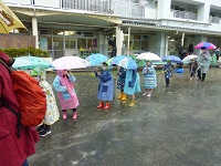 傘をさして出かける子どもの写真