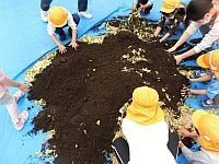 写真:ちぎった野菜と土を混ぜている様子