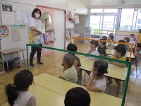 栄養士がそら豆の皮むきを教えている様子の写真