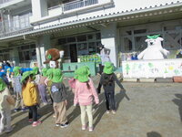 園庭でエコアラ、エコクマと体操をする様子の写真