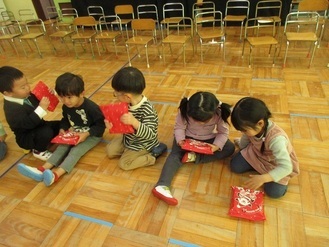 プレゼントの中身が気になる子供たちの様子の写真