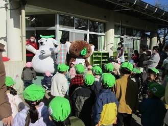 写真：0歳から4歳が園庭でエコクマとエコアラに手を振っている様子