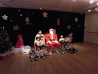 写真:サンタさんと一緒に写真を撮る1歳児