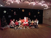 写真:サンタさんと一緒に写真撮影する2歳児