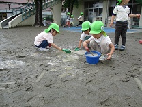 水たまりから、水を集める子どもの写真