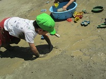 泥に手をついて雑巾がけのように楽しむ子どもの写真