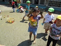 泥んこの手を得意そうに見せる子どもの写真