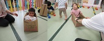 段ボールに入ってぐるぐる回してもらい喜ぶ子どもの写真