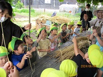 一本ずつ小麦の穂をもらう4歳児の写真