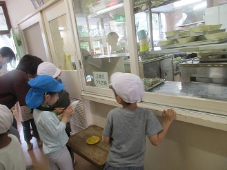 写真：幼稚園と保育園の5歳児が給食室の中をのぞいている様子