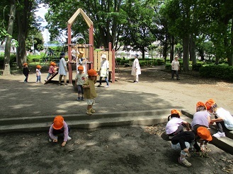 写真：3歳児が公園ですべり台や砂場で遊んでいる様子