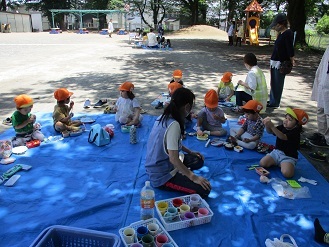 写真：3歳児がみんなでシートに座り、お弁当を食べている様子