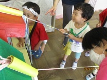 楽しそうにくじの紐を引く3歳児の写真