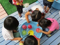 タライからヨーヨーをすくう子供の写真