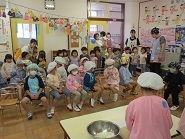 3歳児こあら組が5歳児らいおん組の調理中を見学している様子の写真