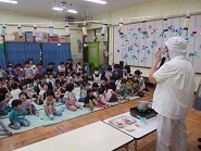 ホールで全クラスがカレー作りのデモンストレーションを見ている様子の写真