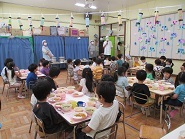 4歳児きりん組と5歳児らいおん組がいただきますの前に調理員のお話を聞いている様子の写真