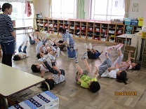 丸くなってみんなでおひさまを表現している子どもの写真