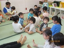 お姉さんの膝で楽しそうな1歳の子どもの写真