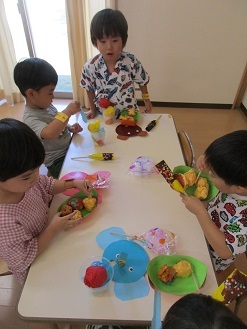 4歳児クラスが5歳児クラスのお店屋さんで注文したものを食べている様子の写真