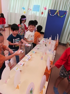 4歳児クラスが5歳児クラスのお店屋さんの射的をしている様子の写真