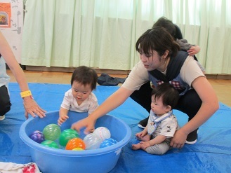 0歳児クラスがヨーヨーすくいをしている様子の写真