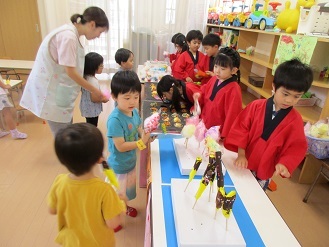 3歳児クラスが5歳児のお店屋さんで食べ物を注文している様子の写真