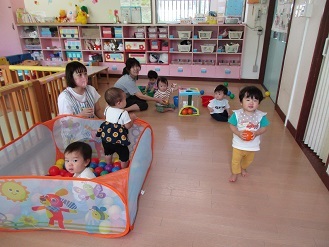 0歳児が保育室でボールプールで遊んでいる様子の写真