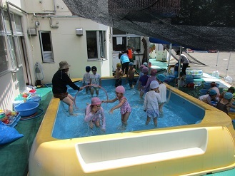 5歳児がプールの中でフラフープをくぐっている様子の写真