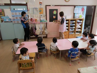 1歳児が誕生会で人形劇を見ている様子の写真