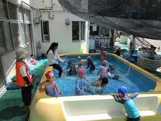 3歳児がプールでフラフープをくぐっている様子の写真