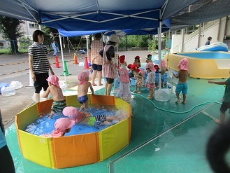 2歳児クラスがビニールプールでプール遊びをしている様子の写真