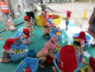 1歳児がテラスで水遊びをしている様子の写真