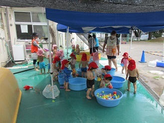 1歳児がタライで水遊びをしている様子の写真