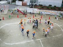 みんなで協力して縄でメリーゴーランドを作る5歳児の写真