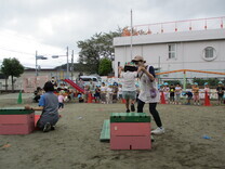 先生と一緒に巧技台からジャンプする2歳児の写真