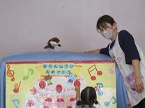 誕生会の出し物、カワウソ君とお話しする保育士の写真
