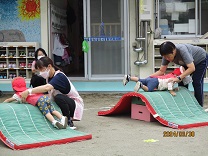 マットの山を乗り越えようと頑張る1歳児の写真