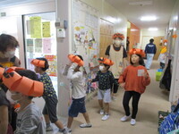 かぼちゃ帽子をかぶって歩いている子どもの写真