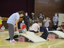 マットのお山をよじ登る1歳児の写真