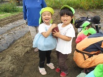 大きなお芋を抱えてはしゃぐ3歳児の写真