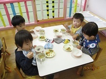保育室で芋汁を食べる1歳児の写真