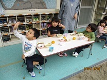 テラスで給食を食べる3歳児の写真
