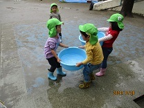タライの水を運ぶ3歳児の写真