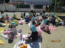 園庭でお弁当給食を楽しむ4歳児の写真